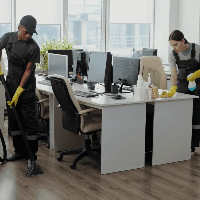 Reinigungskraft wischt einen Schreibtisch im Büro